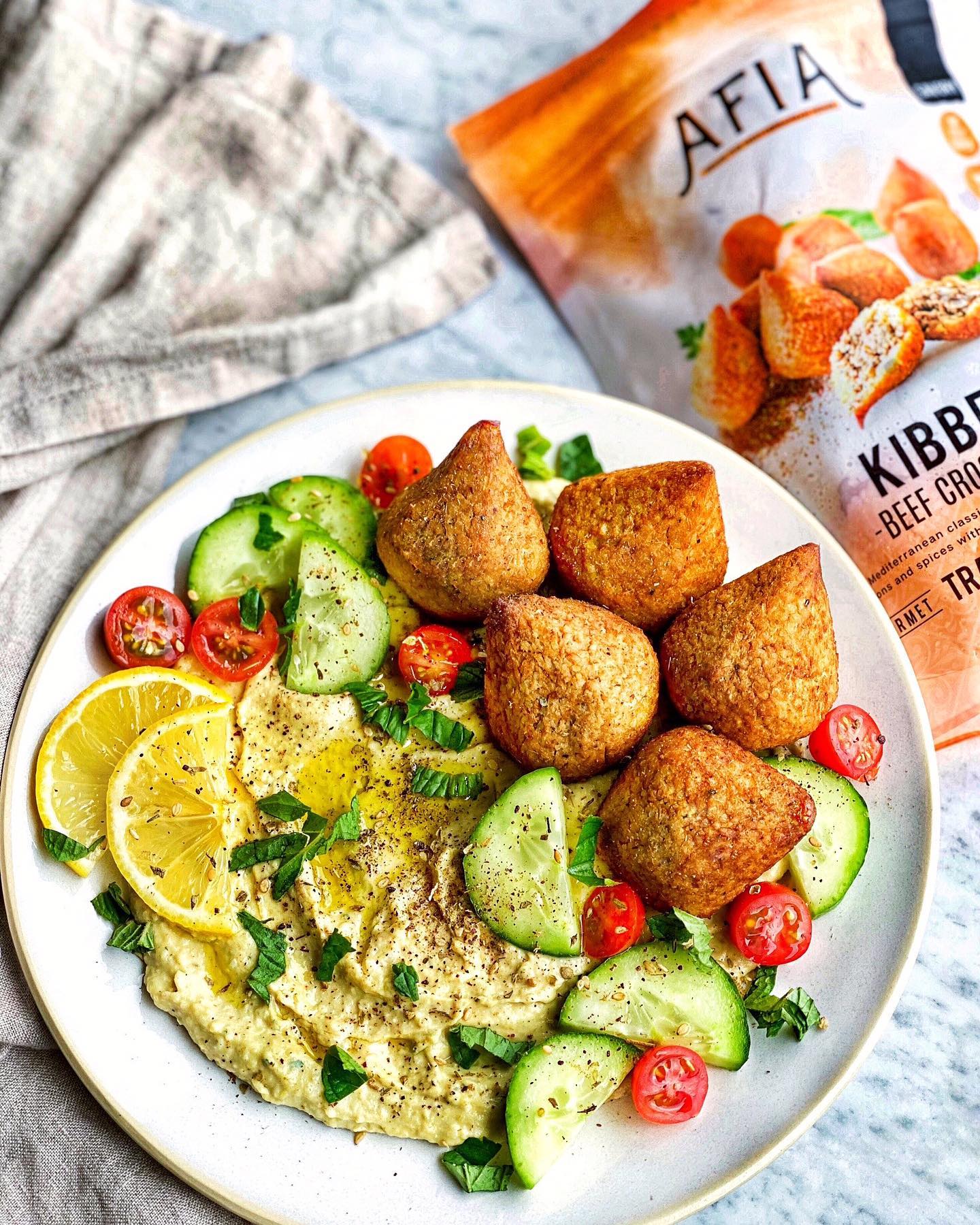 Dip on a platter with cucumbers, lemon slices, and Afia Kibbeh. 