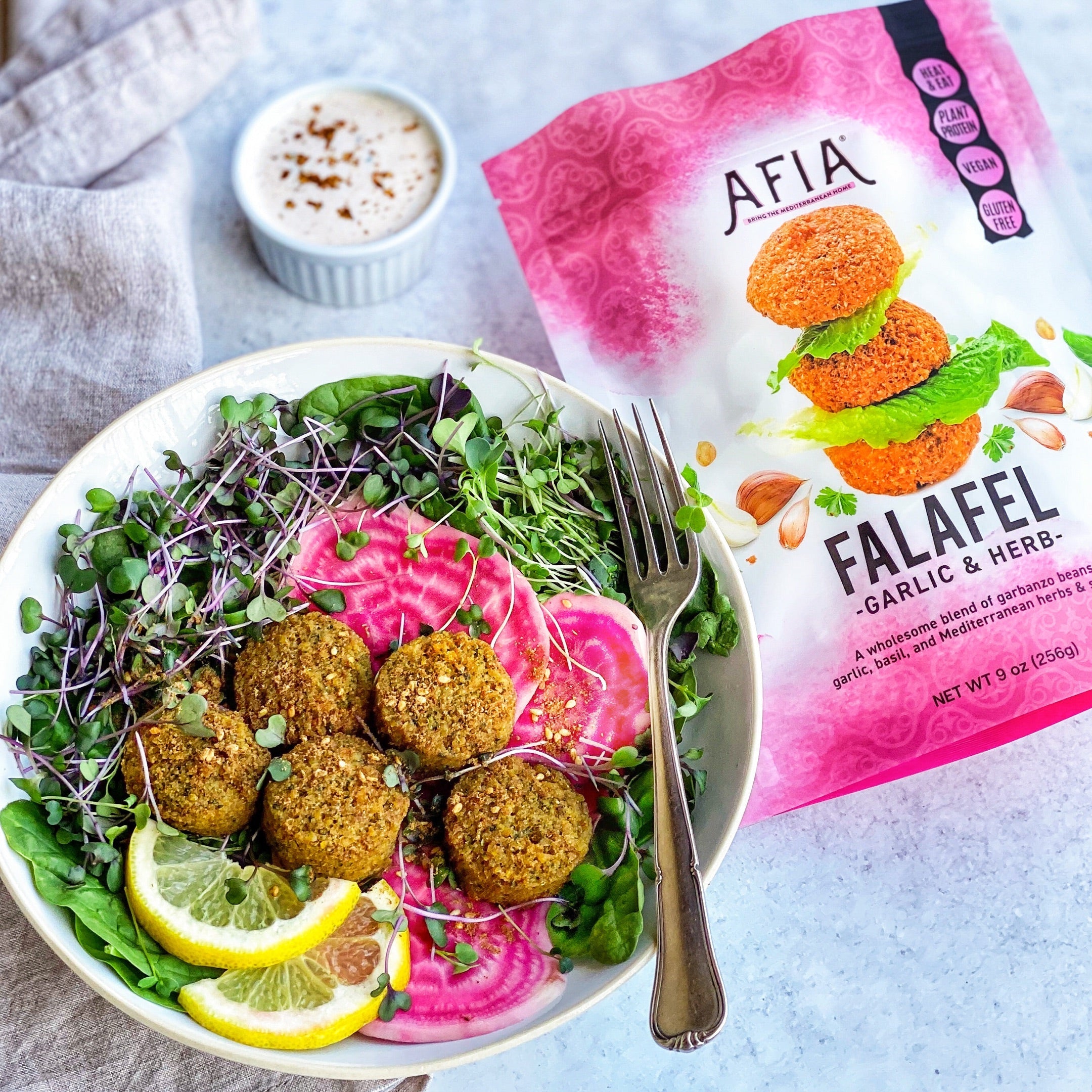 Spinach and sprout salad in a bowl featuring Afia Falafel.