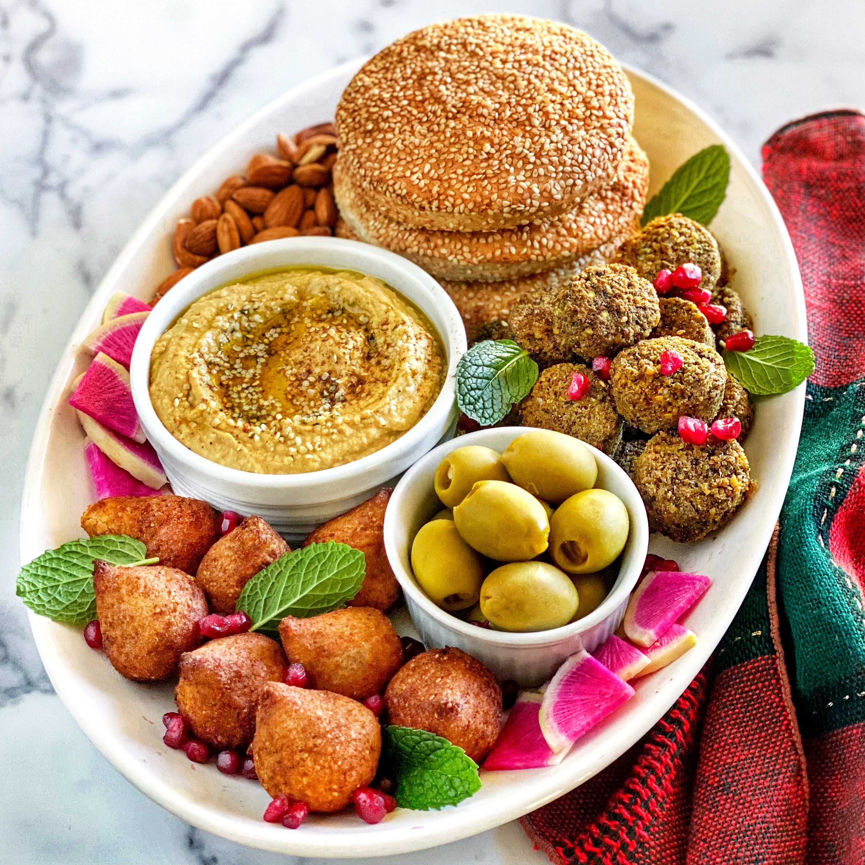Avocado hummus on a platter with olives, and Afia Falafel and Kibbeh. 