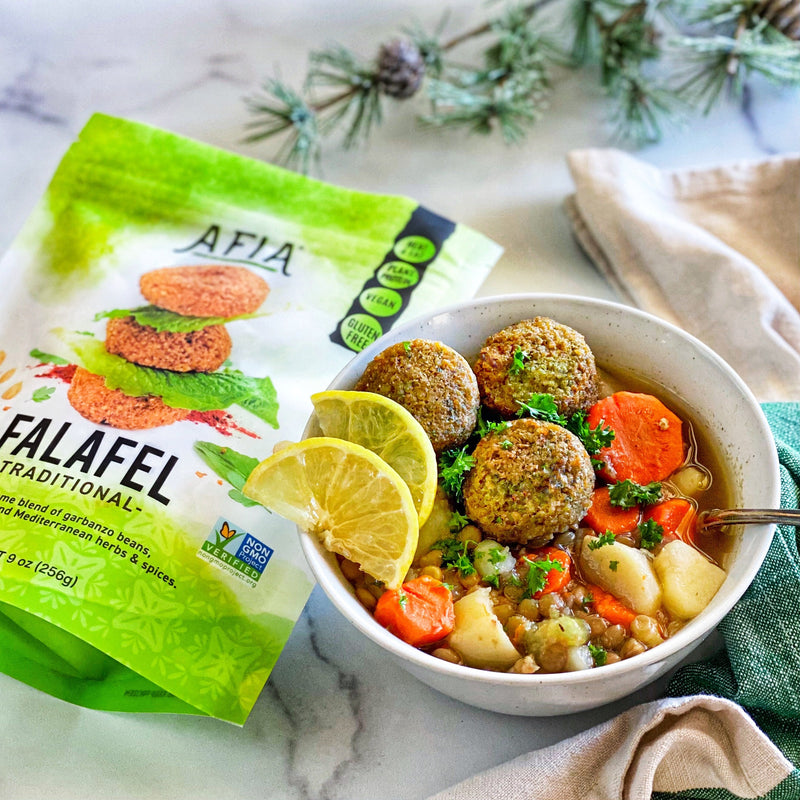 Bowl of lentil soup topped with Afia Falafel and a bag of Afia Falafel on the side. 