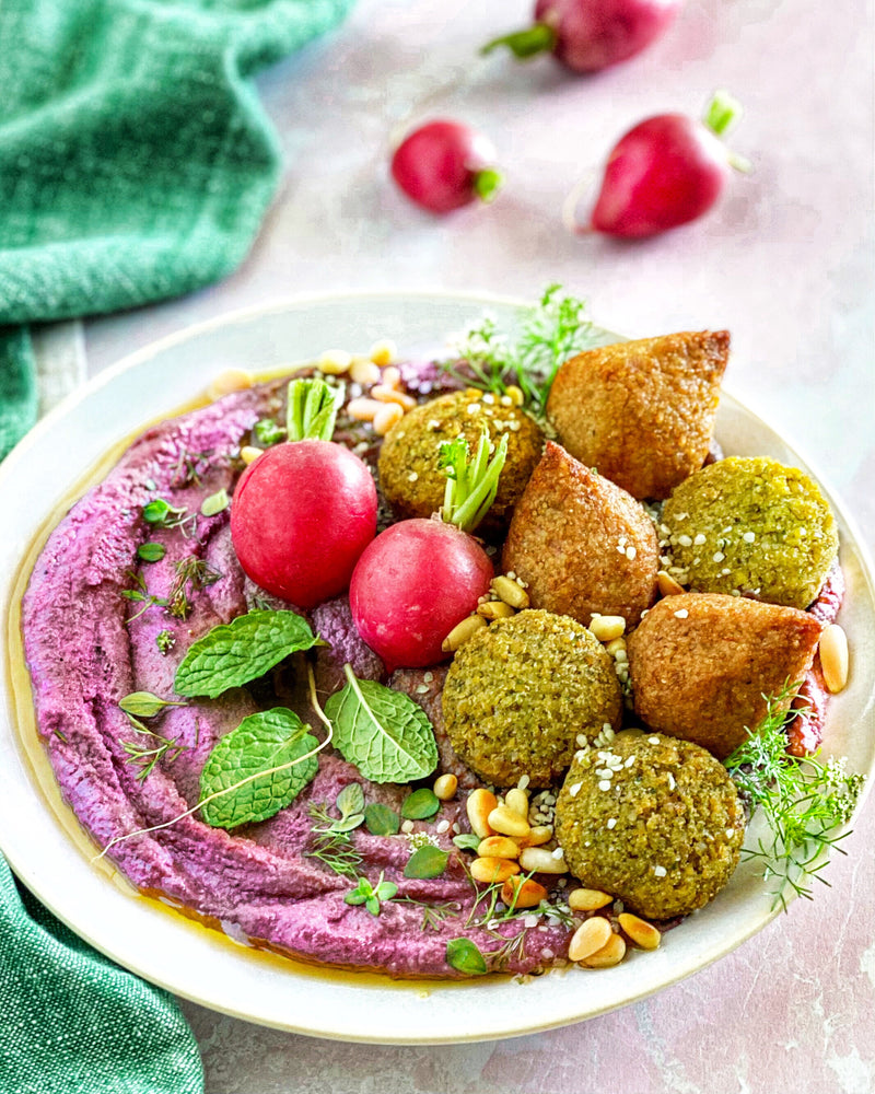 bowl of purple hummus with Afia Falafel, Kibbeh and radishes