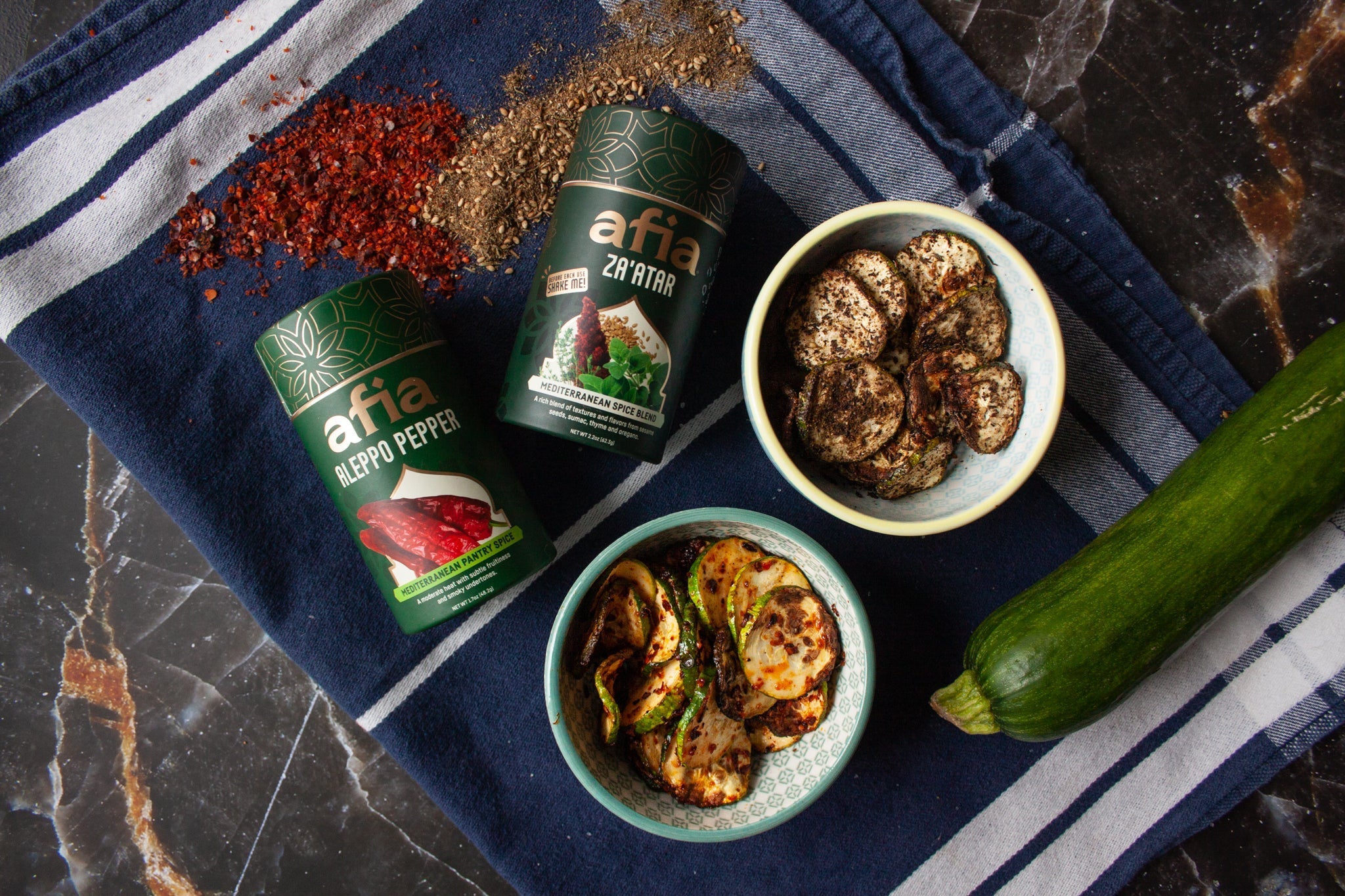 Air Fryer Zucchini chips made two ways, with Afia Za'atar Mediterranean Spice Blend in a white dish and with Afia Aleppo Pepper Mediterranean Pantry Spice in a white dish. 