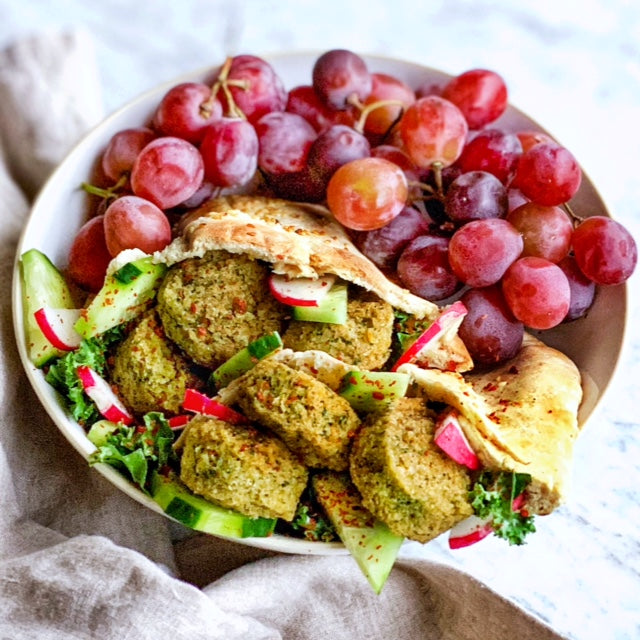 Bowl with pita pocket featuring Afia Falafel and grapes on the side.